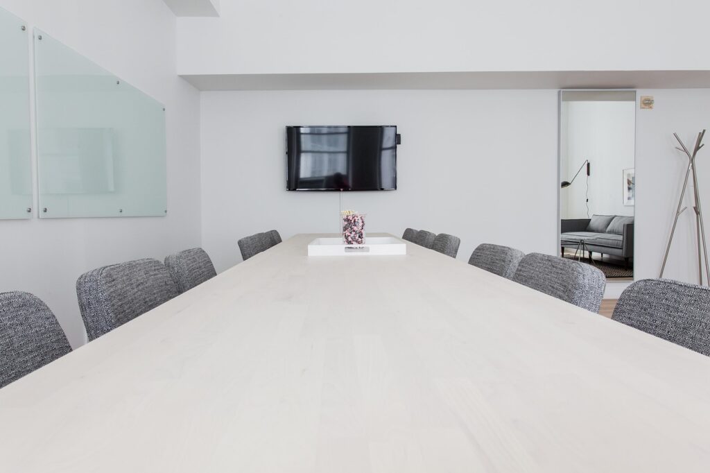 Two professionals shaking hands across a conference table with documents