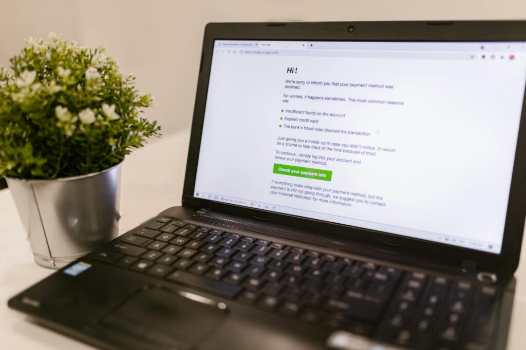 Phone showing payment alerts next to laptop displaying declining revenue charts