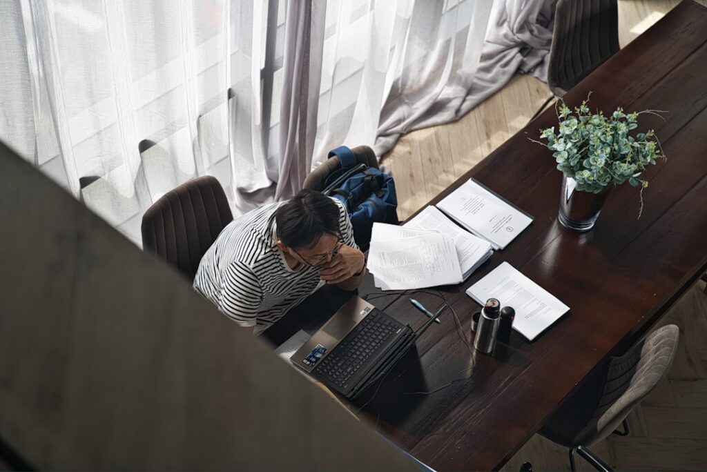 Landscaping business owner stressed at desk with multiple MCA contracts spread out