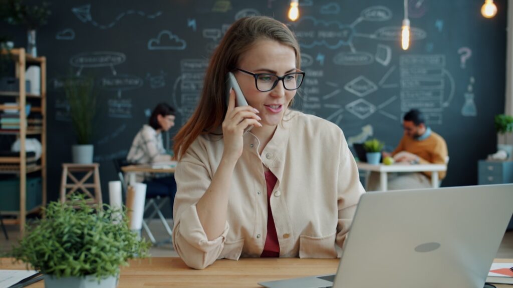 Small business owner on a phone call looking confident and relieved at their desk