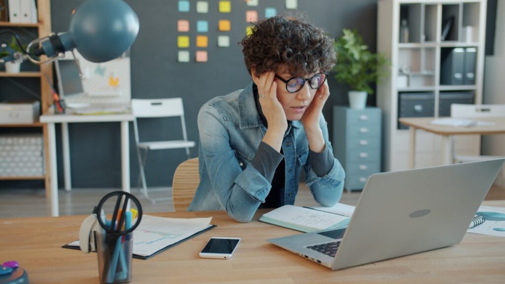 Stressed retail boutique owner at desk surrounded by multiple MCA contracts and invoices