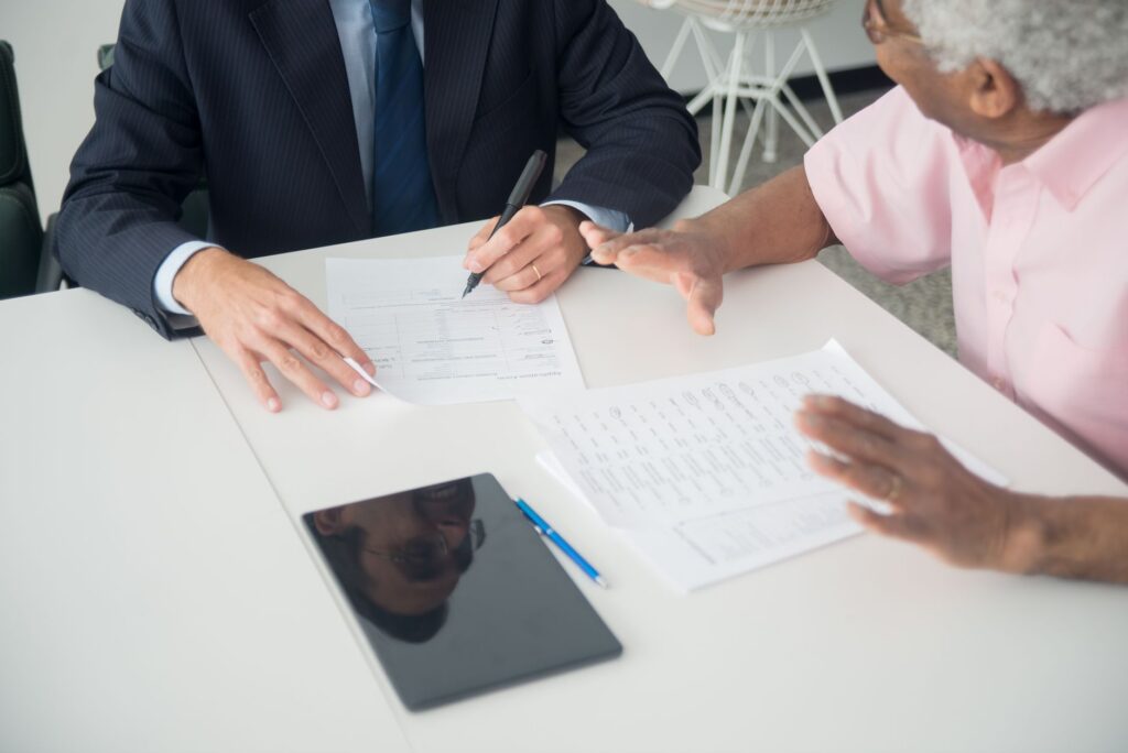 Two people negotiating MCA settlement across a small business desk with documents