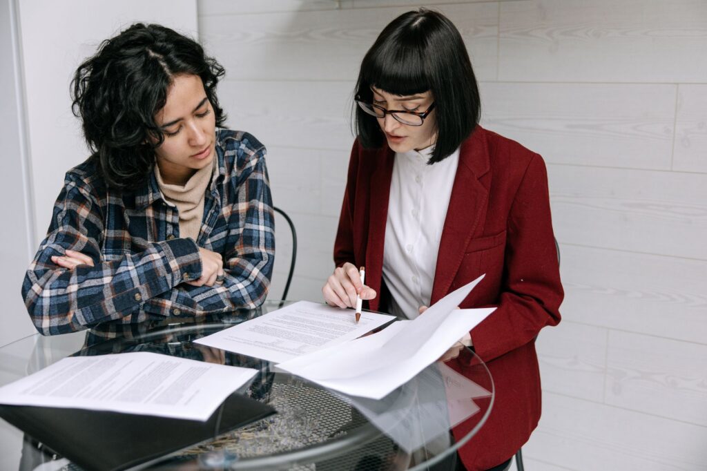 Business owner and advisor reviewing MCA settlement terms and resolution documents at office table