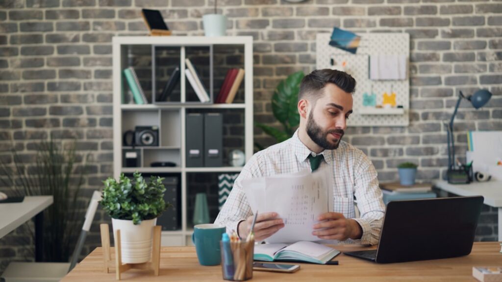 Small business owner reviewing mid-year financial statements and MCA payment records