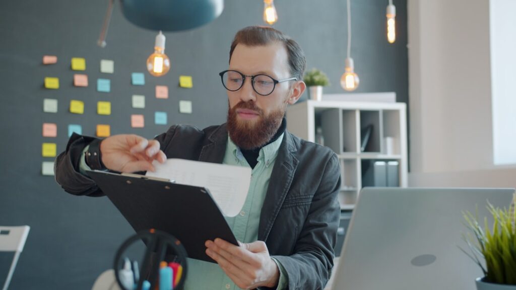 Small business owner looking stressed at desk covered with financial documents