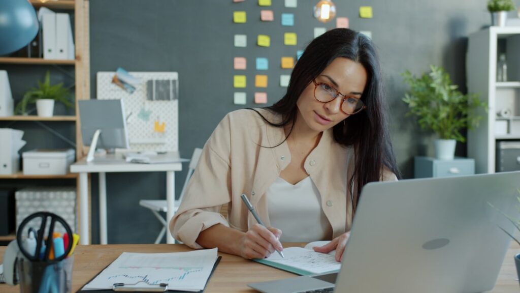 Small business owner reviewing stacked MCA debt paperwork at desk