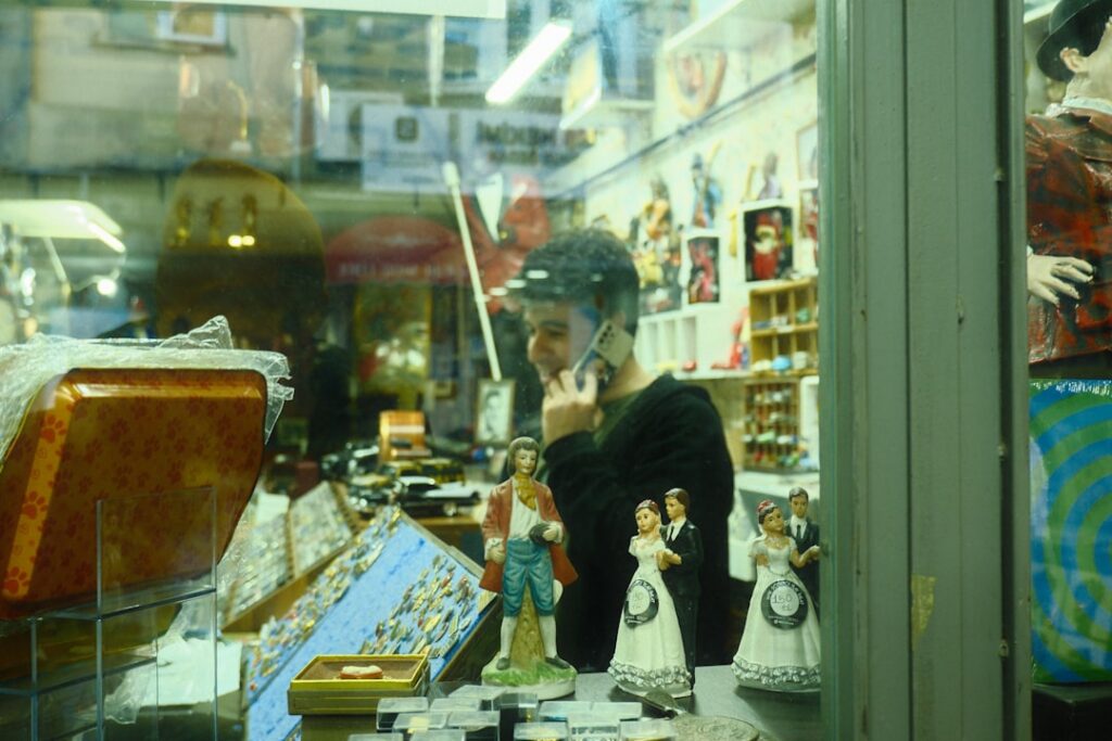 Small business owner standing at storefront window reviewing financial paperwork