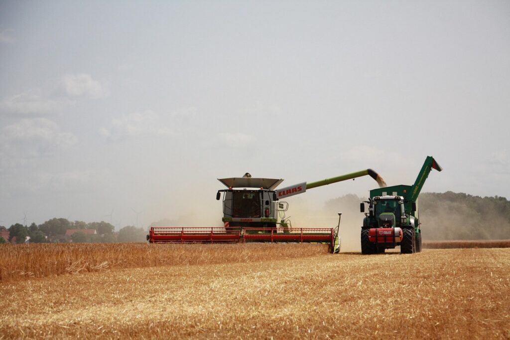 Farmer harvesting a crop with a combine at sunset