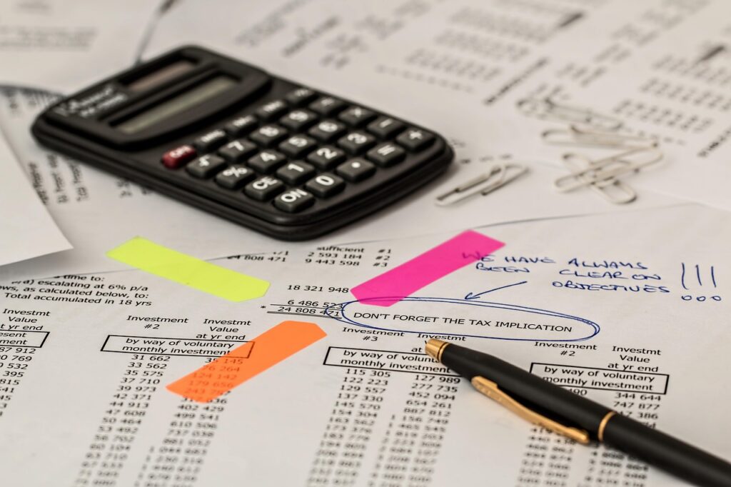 Calculator and stack of brewery supplier invoices on an office desk