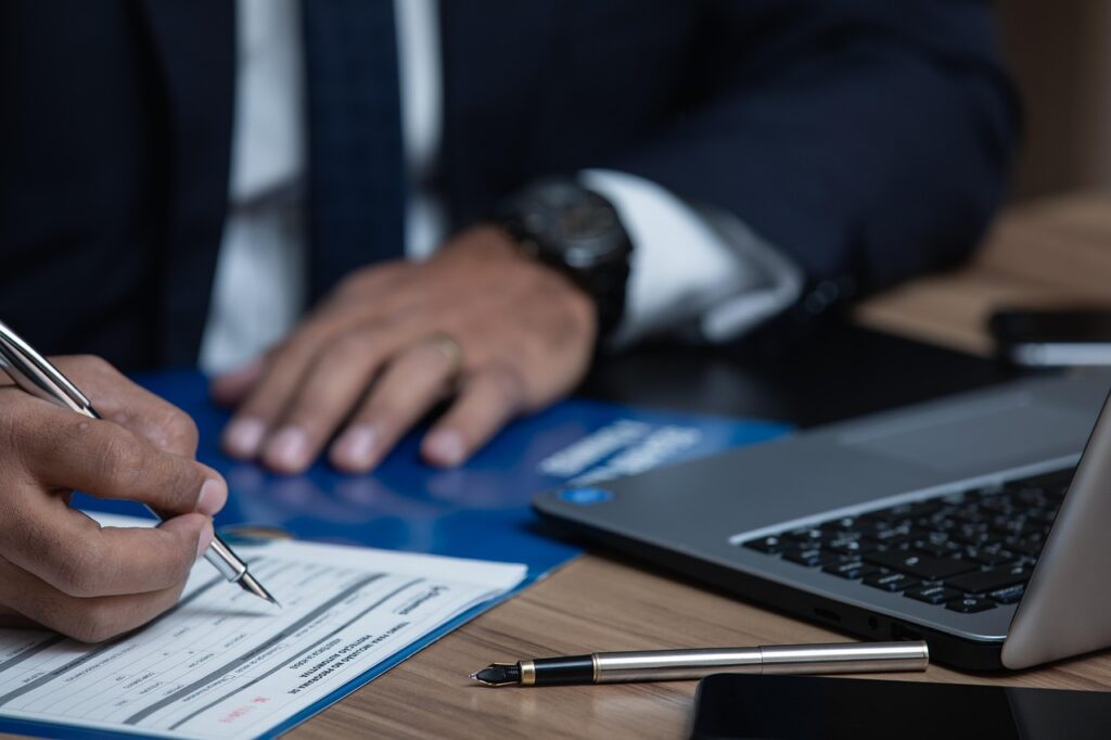Business owner reviewing and signing contract paperwork at a small office desk