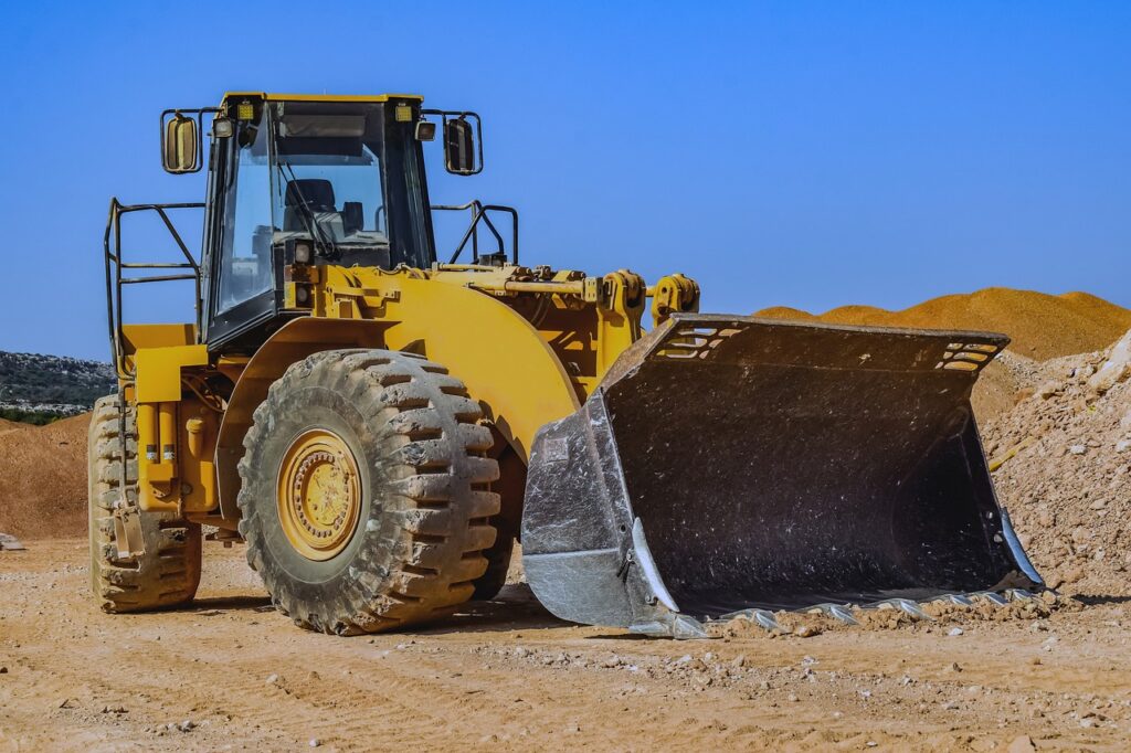 Construction equipment on a jobsite with the owner reviewing financing paperwork nearby