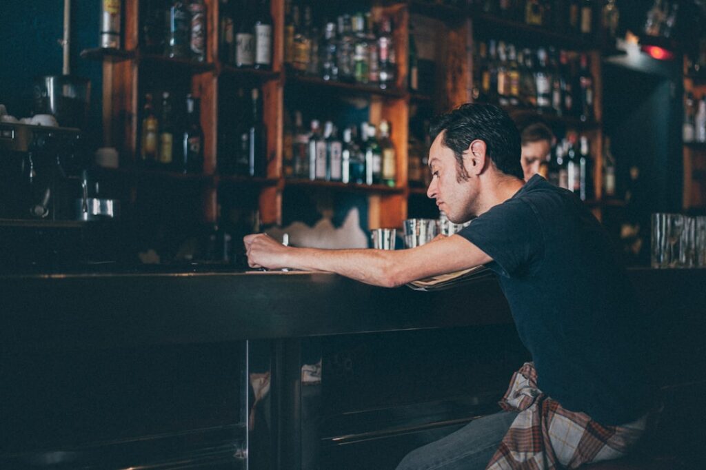 Bar owner reviewing bills and a laptop at the counter late at night