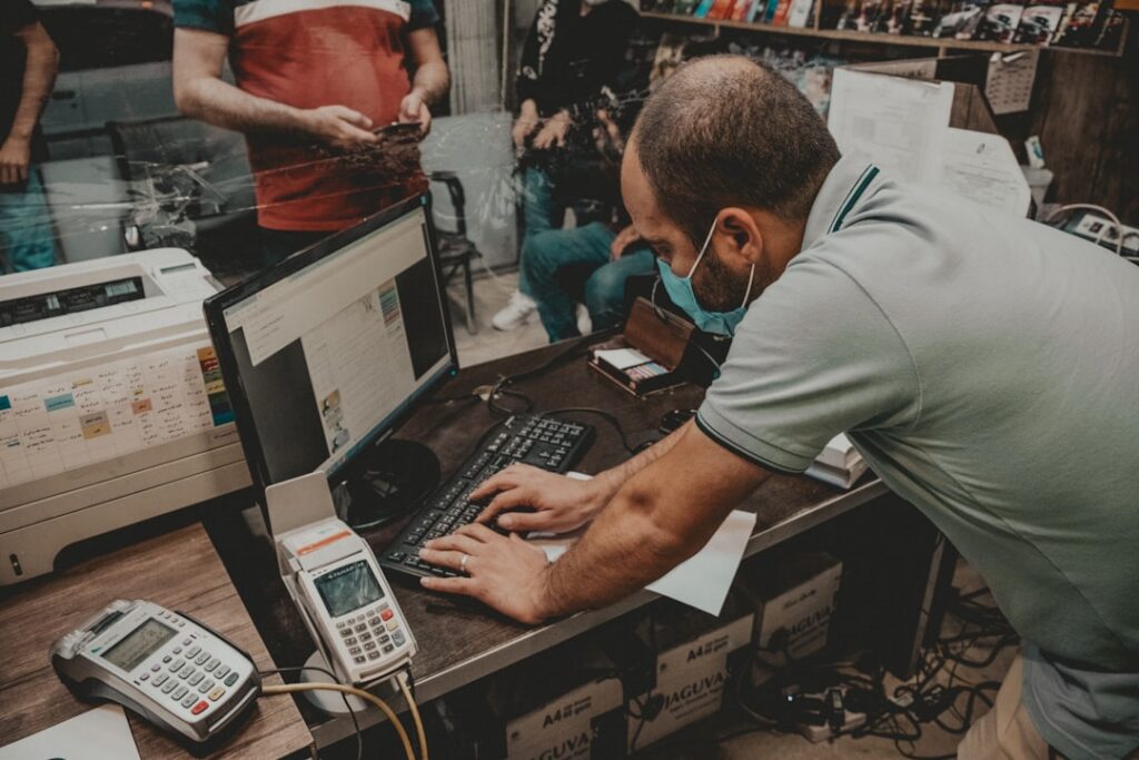 Business owner reviewing bank statements and using a calculator at a desk