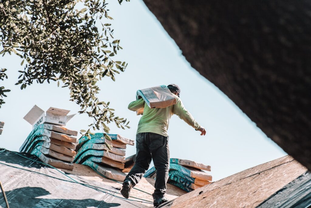 Roofing contractor reviewing an insurance claim document while standing on a ladder against a house