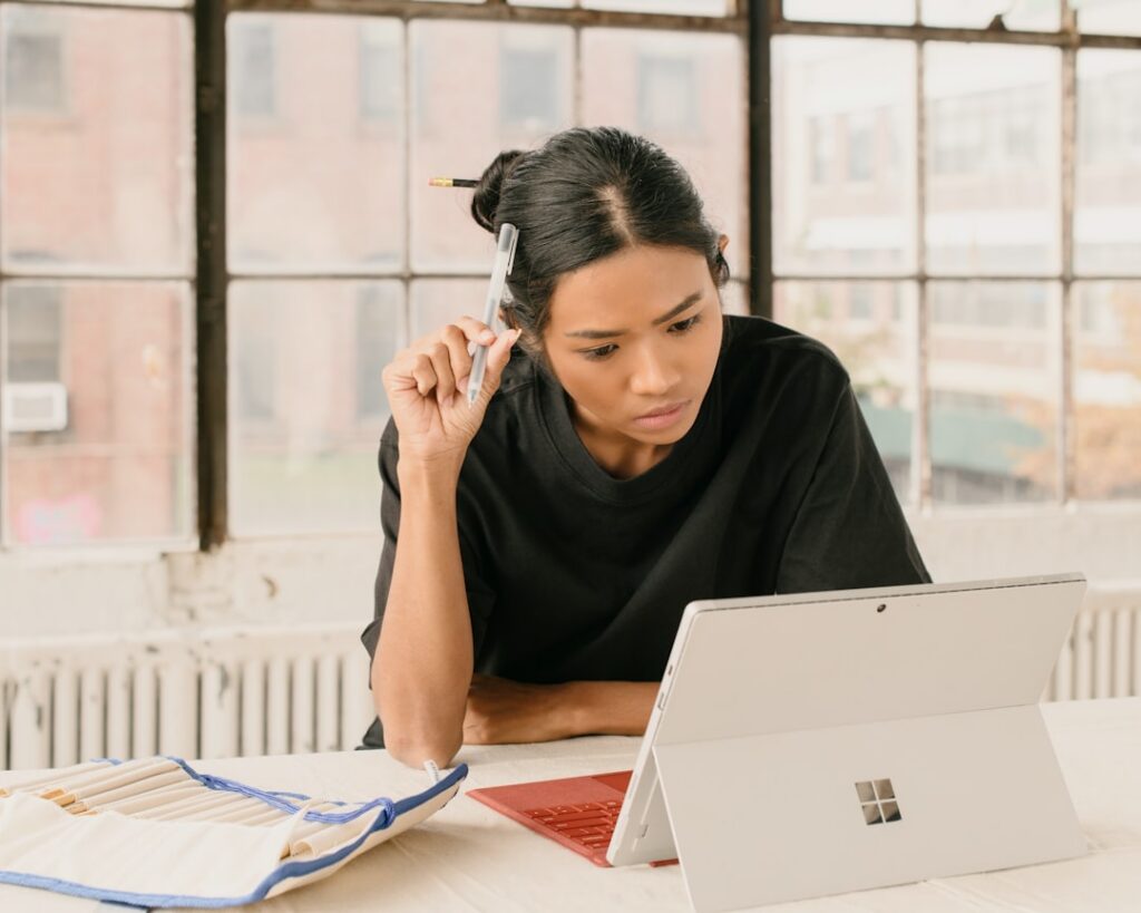 Small business owner looking concerned at a laptop screen with financial paperwork nearby