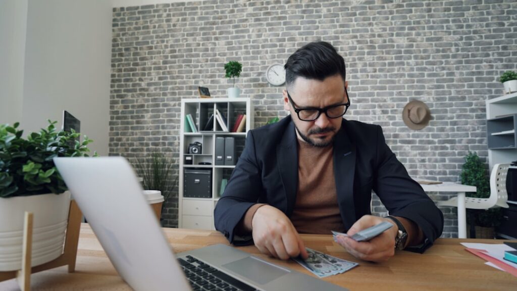 Business owner calculating a daily debit schedule against bank deposit statements