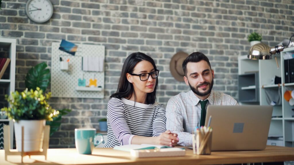 Two business co-owners reviewing a stack of financial paperwork together at a desk