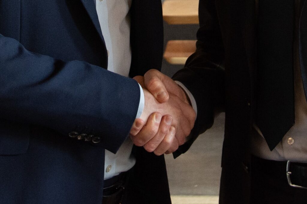 Advisor and small business owner shaking hands over a settlement agreement