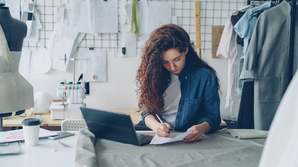 Business owner signing new financing paperwork with a laptop open on the desk
