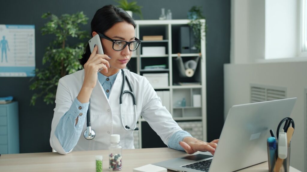 Pharmacist reviewing a stack of bills and funder statements at the office desk