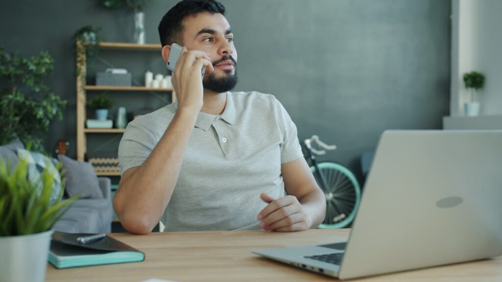 Small business owner on the phone negotiating while reviewing figures on a laptop