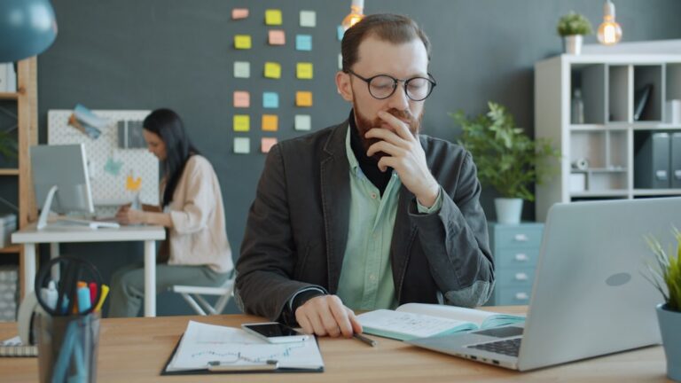 Business owner reviewing a stack of vendor invoices next to a laptop