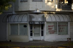 Small business owner boarding up storefront windows ahead of a hurricane