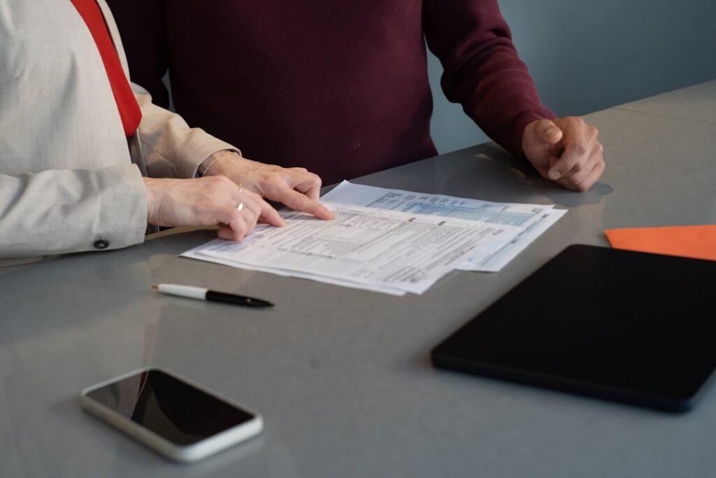 Two people negotiating terms across a desk with paperwork