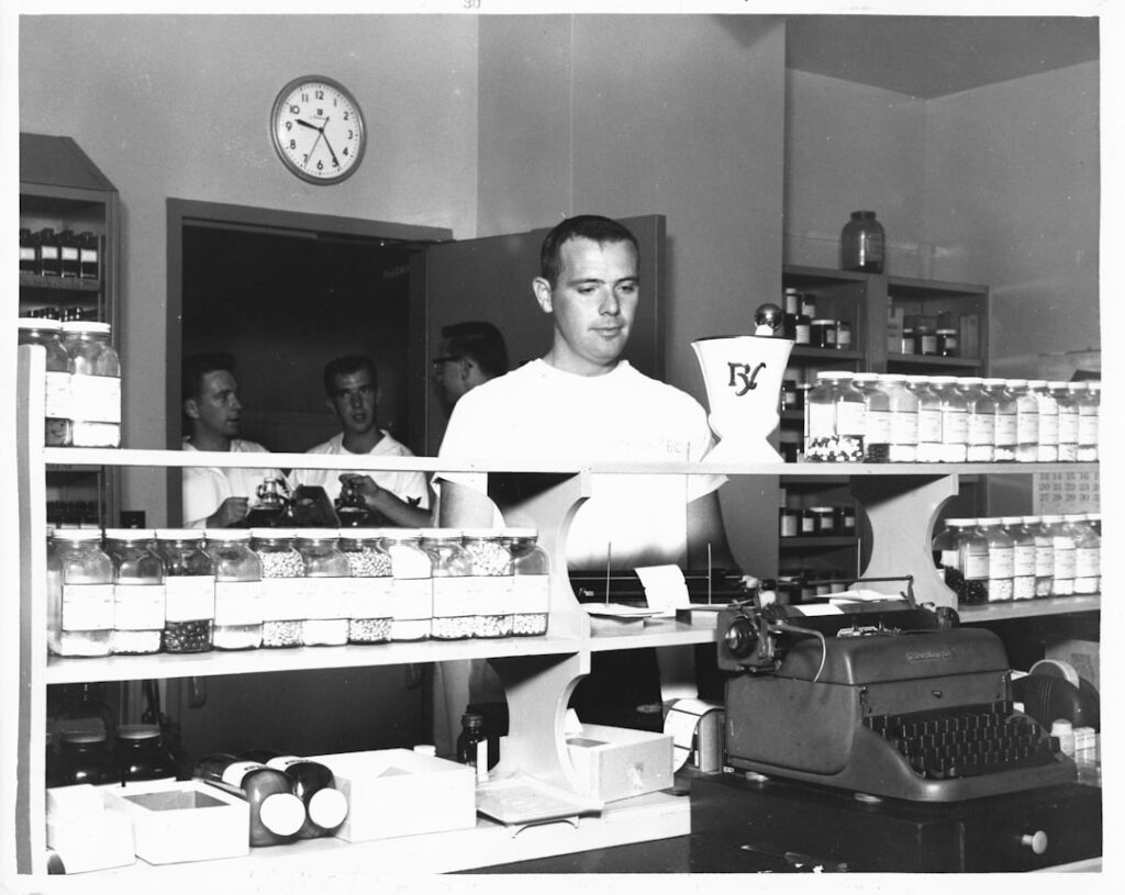 Independent pharmacist checking prescription bottles behind the counter