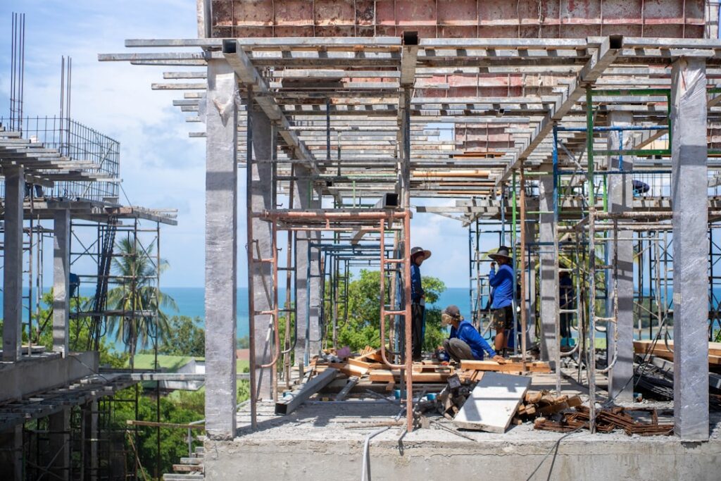 Confident contractor standing at a construction site with a completed project