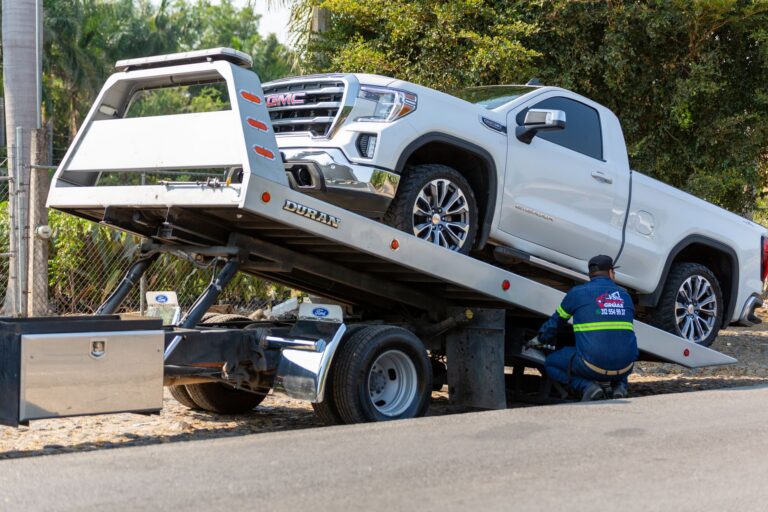 Tow truck operator reviewing invoices and paperwork near a flatbed truck