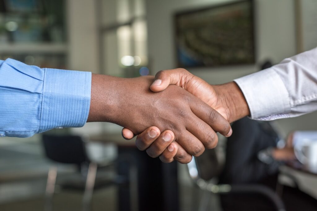 Business owner and advisor shaking hands across a desk after reaching an agreement