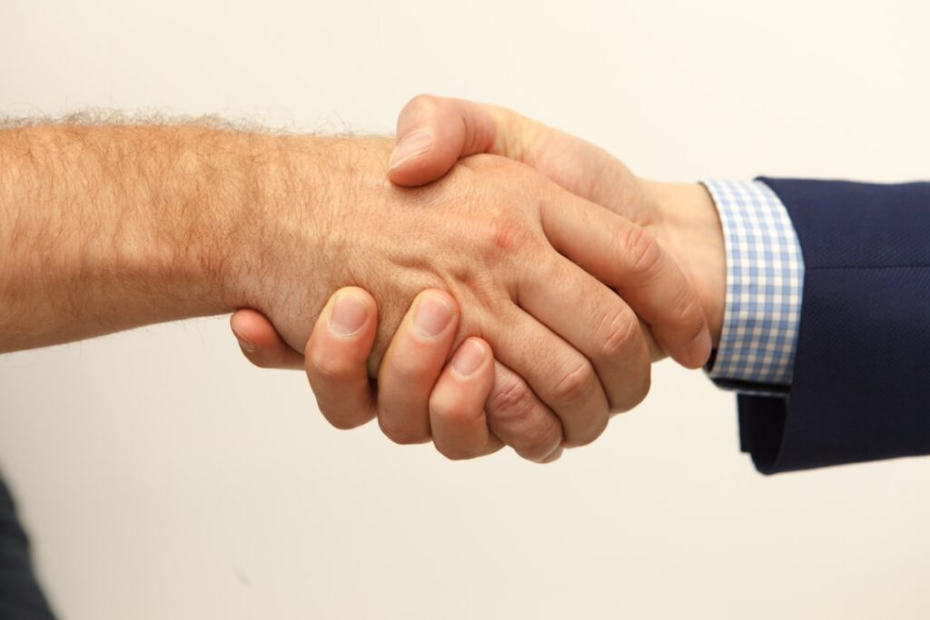 Two professionals shaking hands after reaching a negotiated settlement agreement