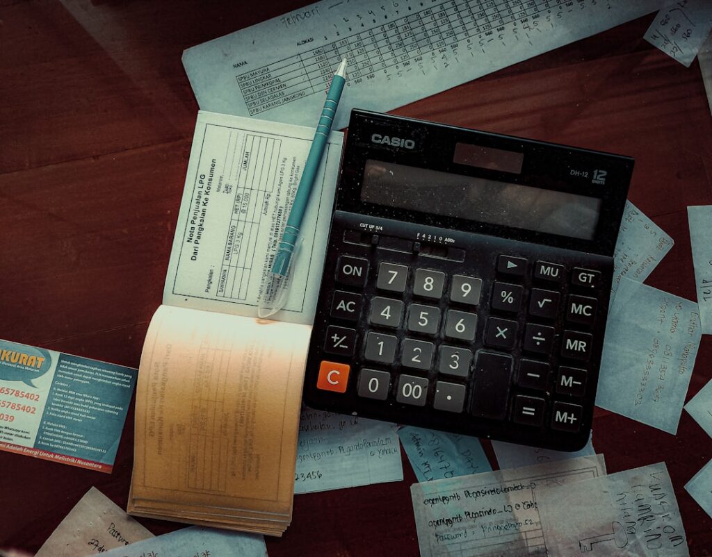 Calculator and invoices on a desk next to merchant cash advance contract paperwork