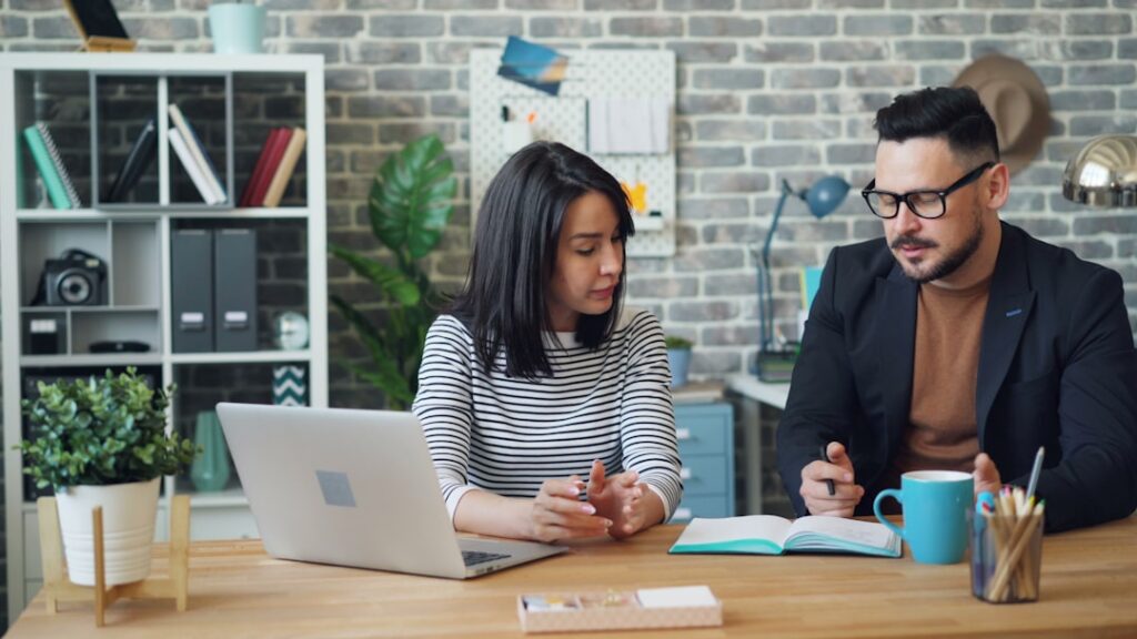 Two people reviewing settlement paperwork and a calculator across a desk