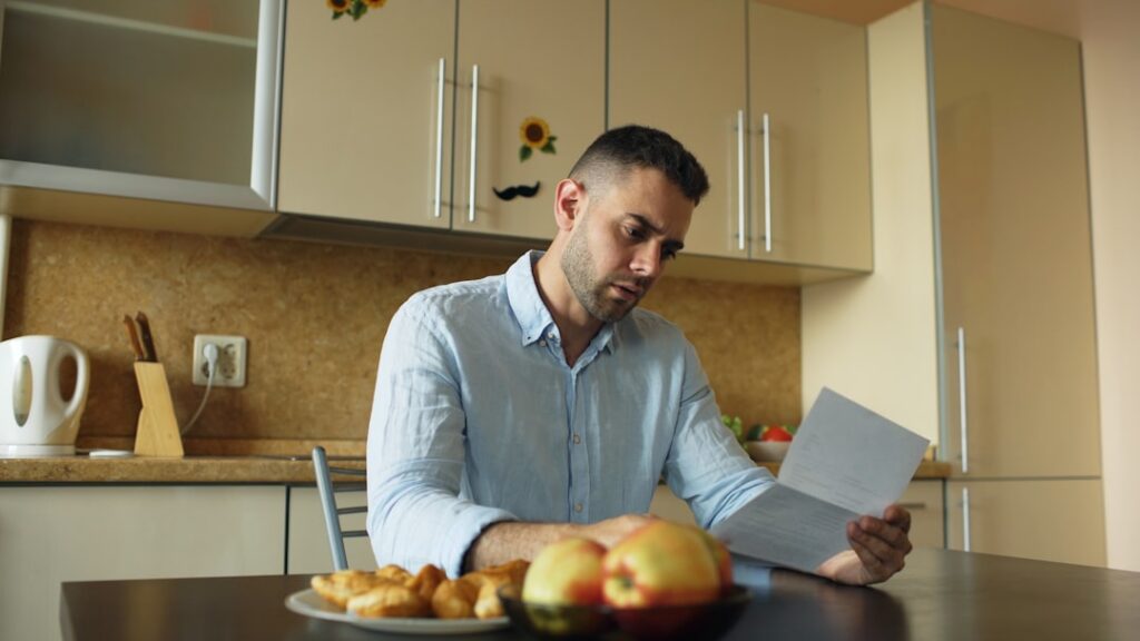 Business owner opening mail at a kitchen table early in the morning