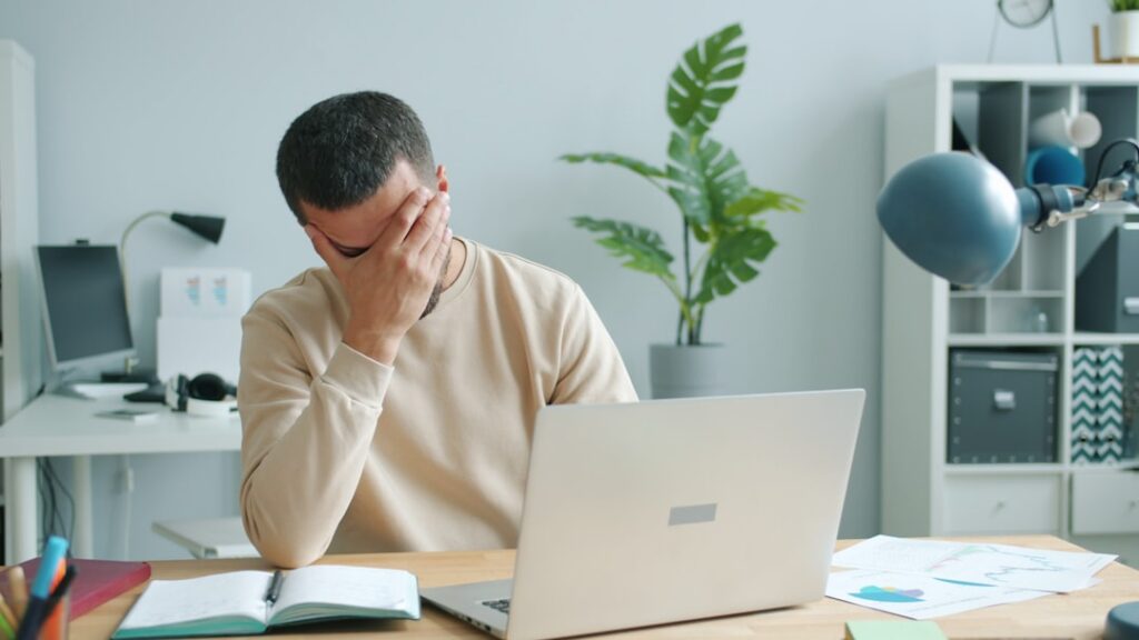 Stressed business owner reviewing a stack of financing contracts at a desk