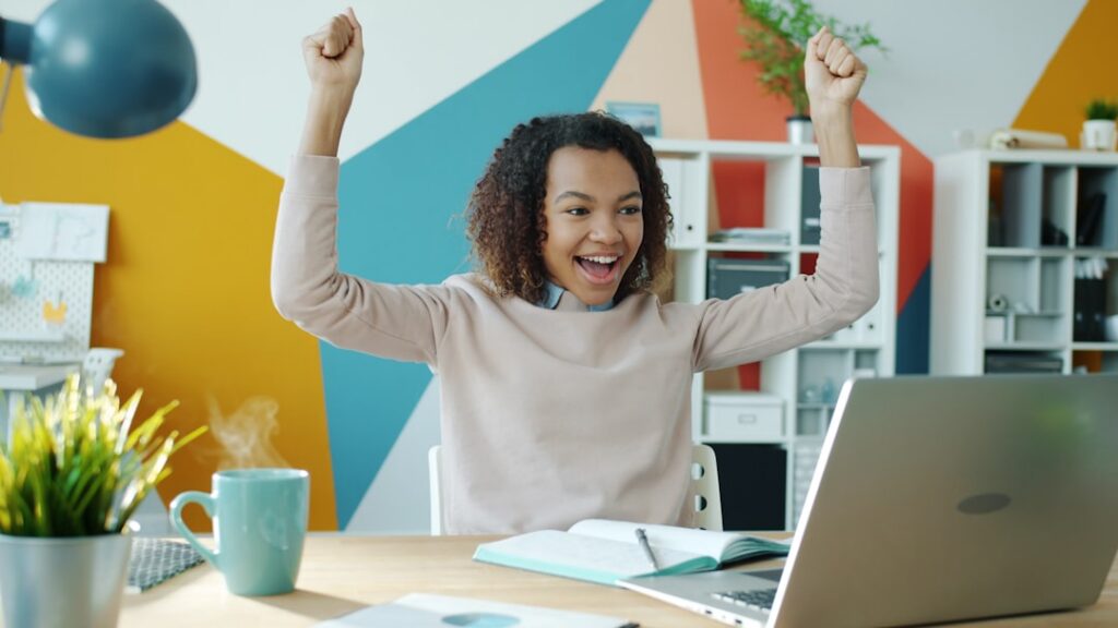 Small business owner appearing relieved while reviewing paperwork at a laptop