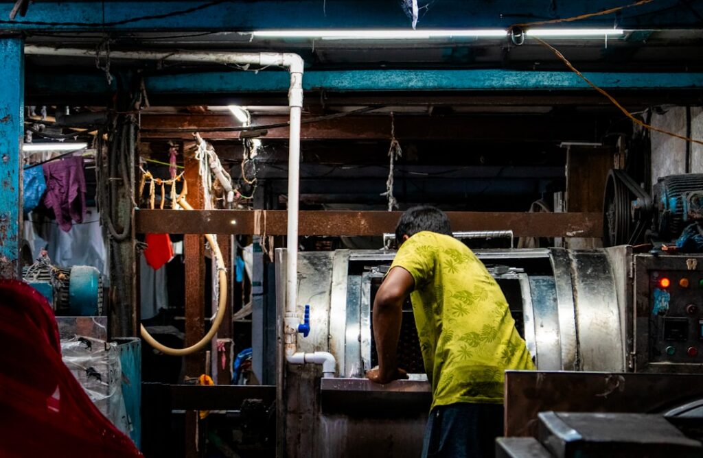 Technician repairing a commercial dryer bank in a laundromat
