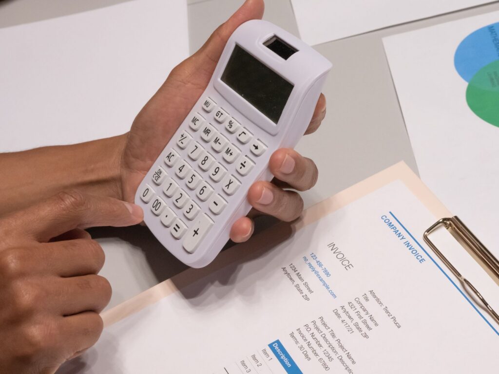 Calculator and stack of invoices on a contractor's desk