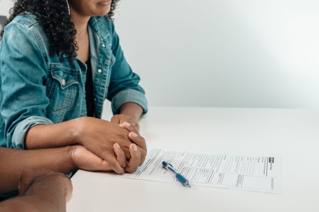 Two people signing a settlement agreement at a small office desk