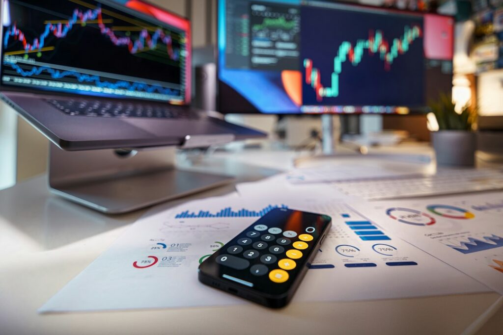 Laptop displaying financial charts next to a calculator on an office desk