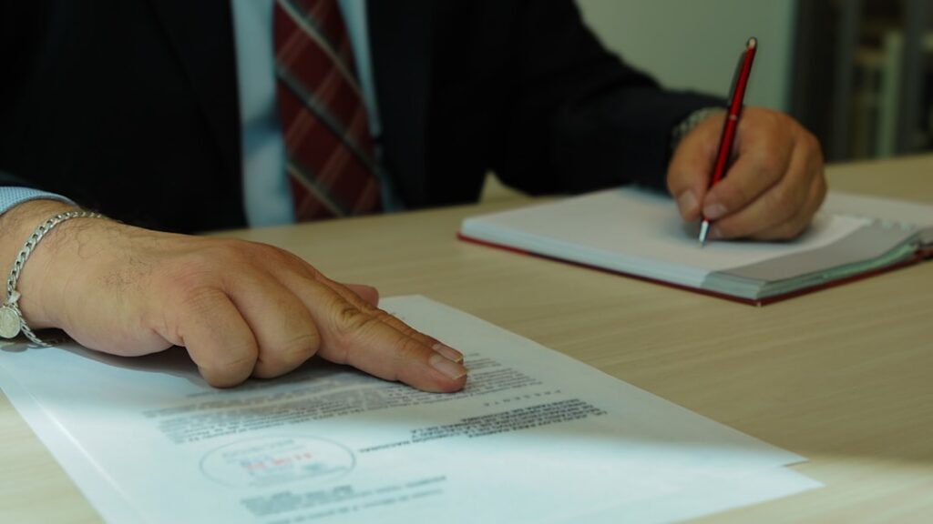 Close-up of a hand signing a commercial financing disclosure document