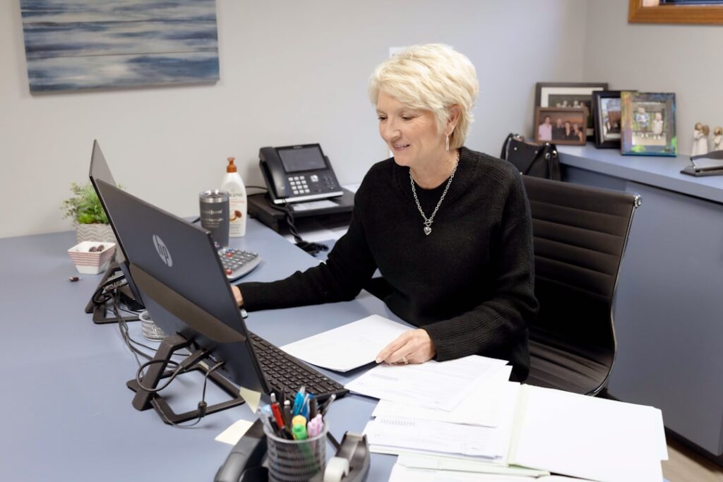Funeral home owner on the phone reviewing invoices at a desk