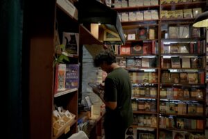 Small gift shop owner checking paperwork beside boxes of holiday inventory