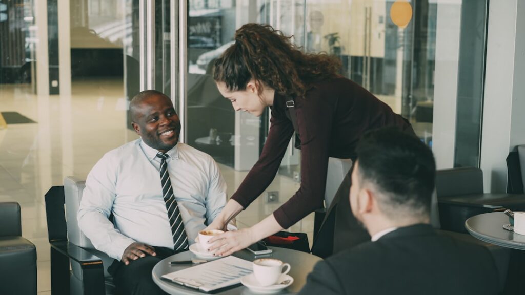 Two people shaking hands across a table after reaching a negotiated agreement