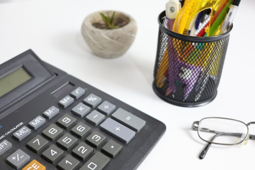 Calculator and payroll spreadsheet next to daily sales receipts on a business owner's desk