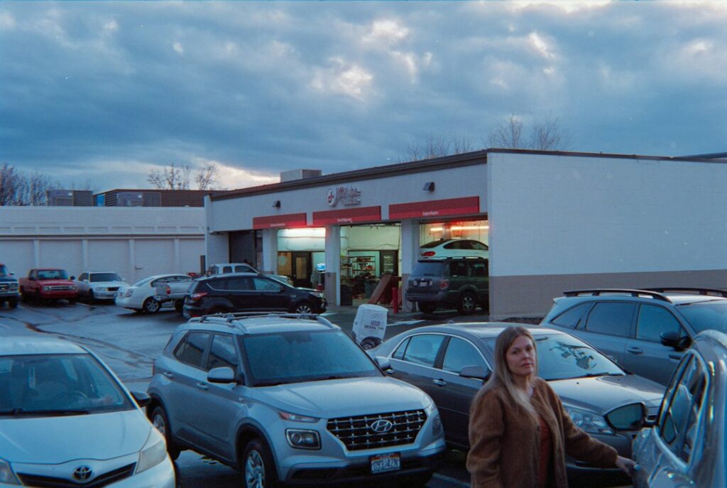 Rows of used cars on a dealership lot with a small sales office