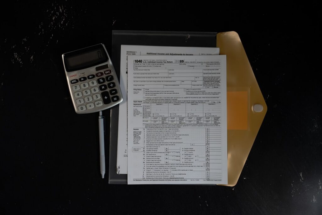 Contractor calculating expenses and tax obligations with a calculator and invoices