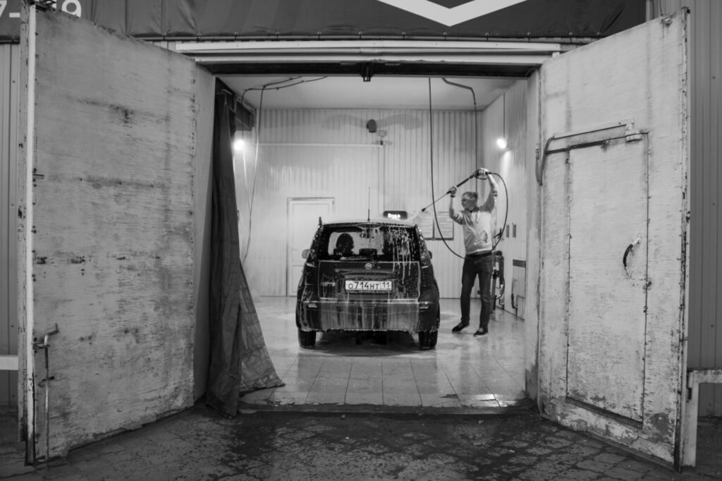 Car wash owner inspecting equipment in a wash bay